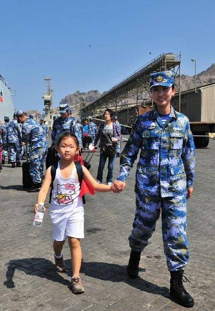 2015年3月，也门，海军女战士牵着一名小女孩的手准备登上军舰。